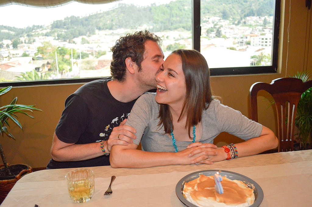 A man kisses a woman in front of a birthday cake