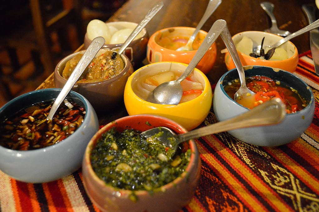 Many small bowls of sauces and vegetables on a table