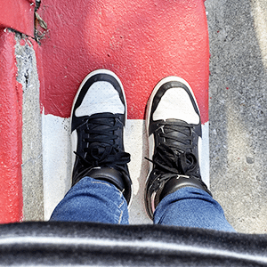 Black and white sneakers standing on red and white painted cement