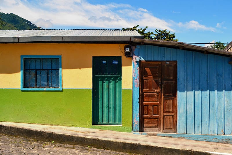 A yellow, green, and blue painted house on a hill in Ecuador