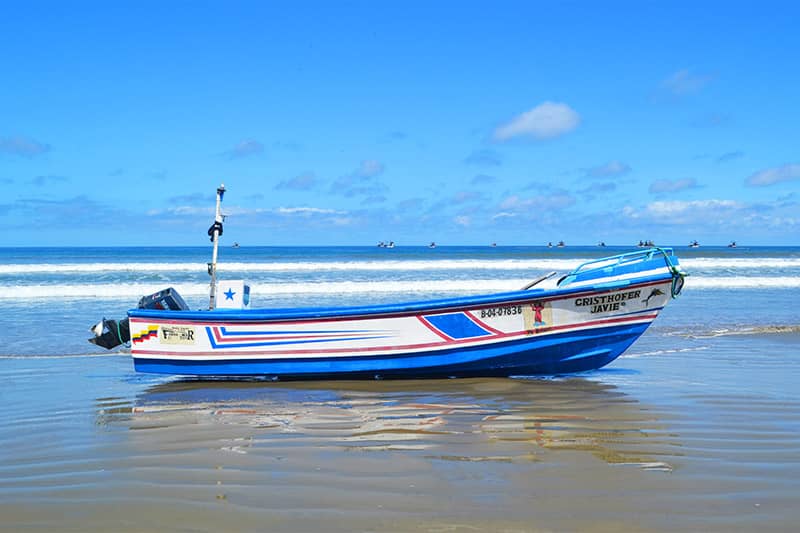 A blue and white boat on a beach with blue skies
