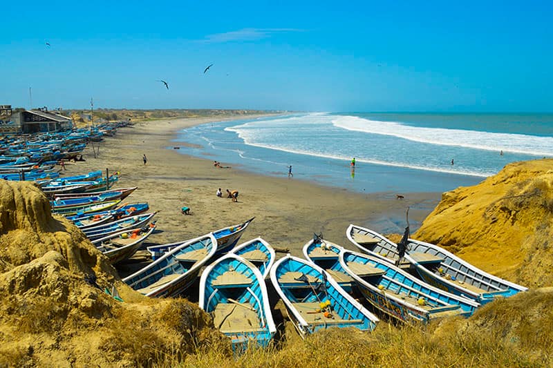 A picturesque scene of blue boats on the beach of Playas, Ecuador