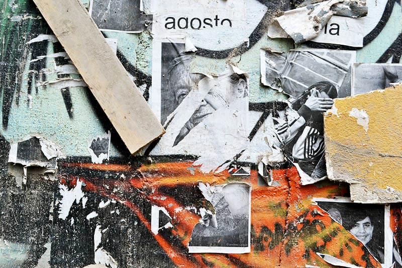 A close up of a wall of posters and graffiti in Ecuador