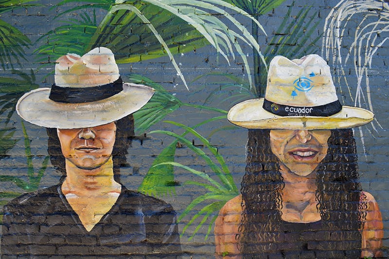 An image of a mural in Cuenca, Ecuador of two people wearing Panama hats