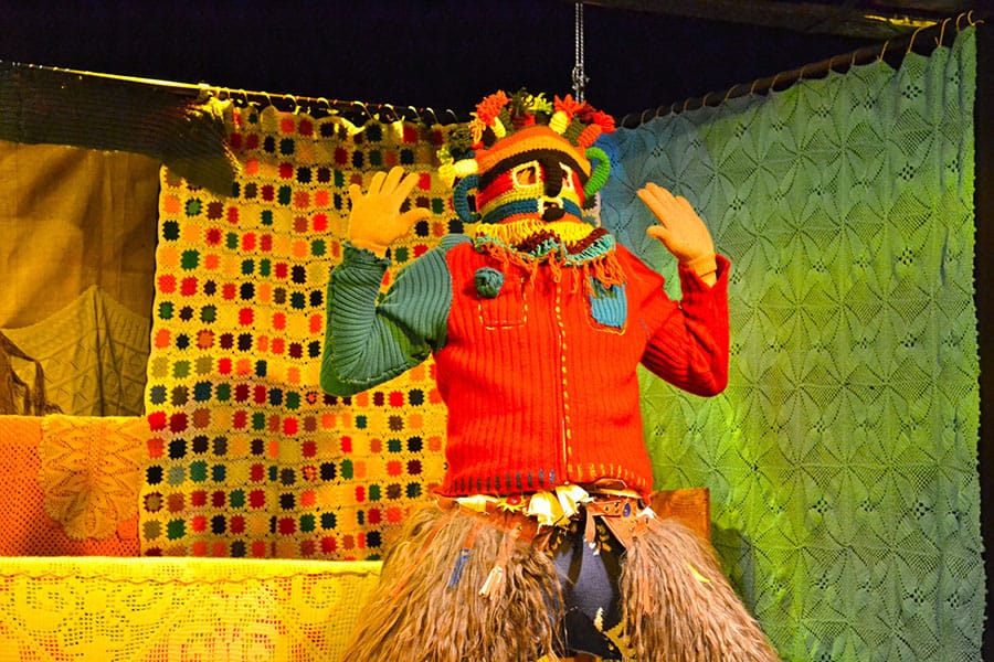 An actor in a crocheted Aya Huma dual faced mask performs on stage in Cuenca, Ecuador