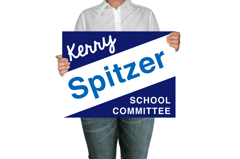 A person holds a lawn sign advertising Kerry Spitzer for Amherst School Committee